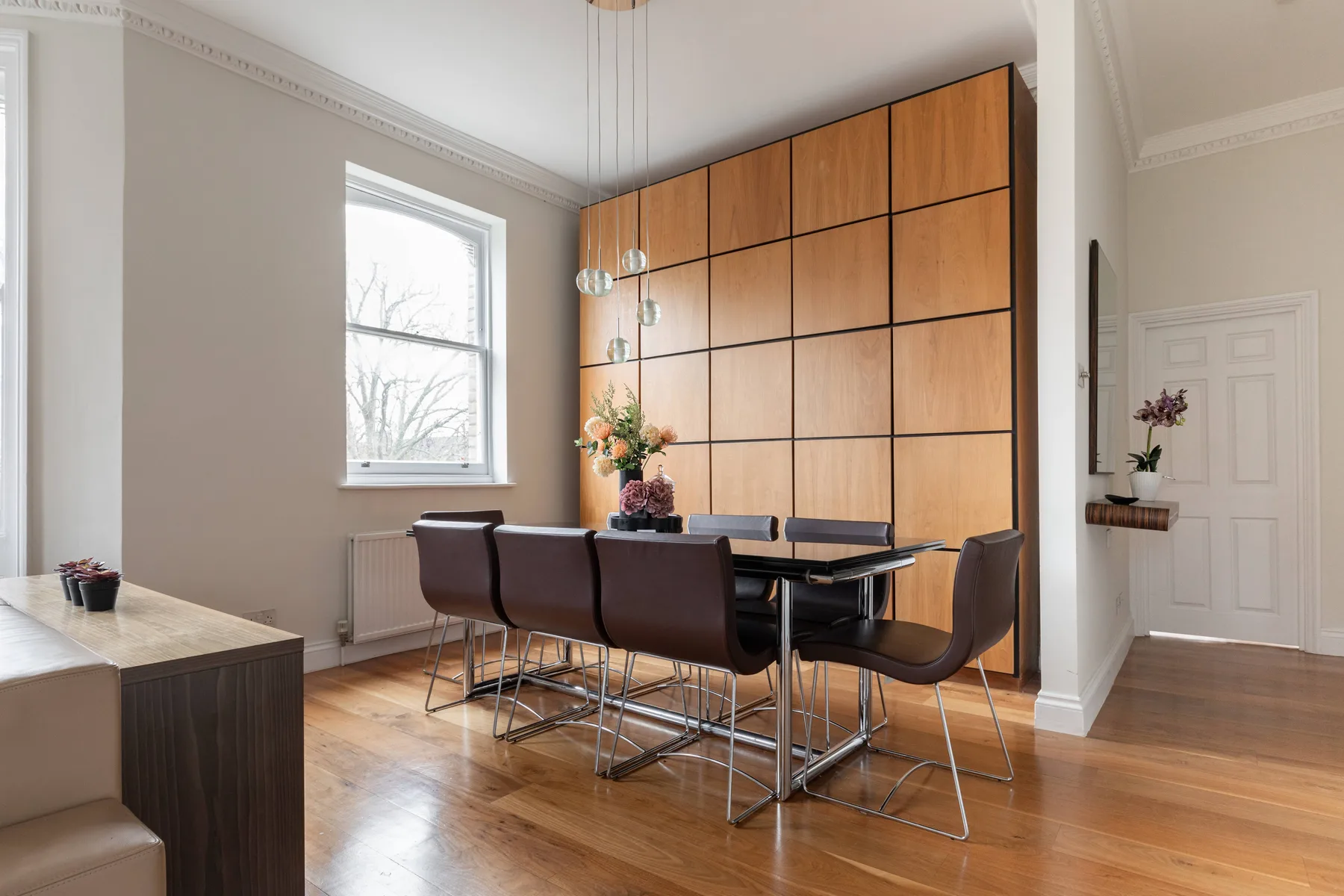 Un comedor con una mesa y sillas junto a un gran panel de madera.