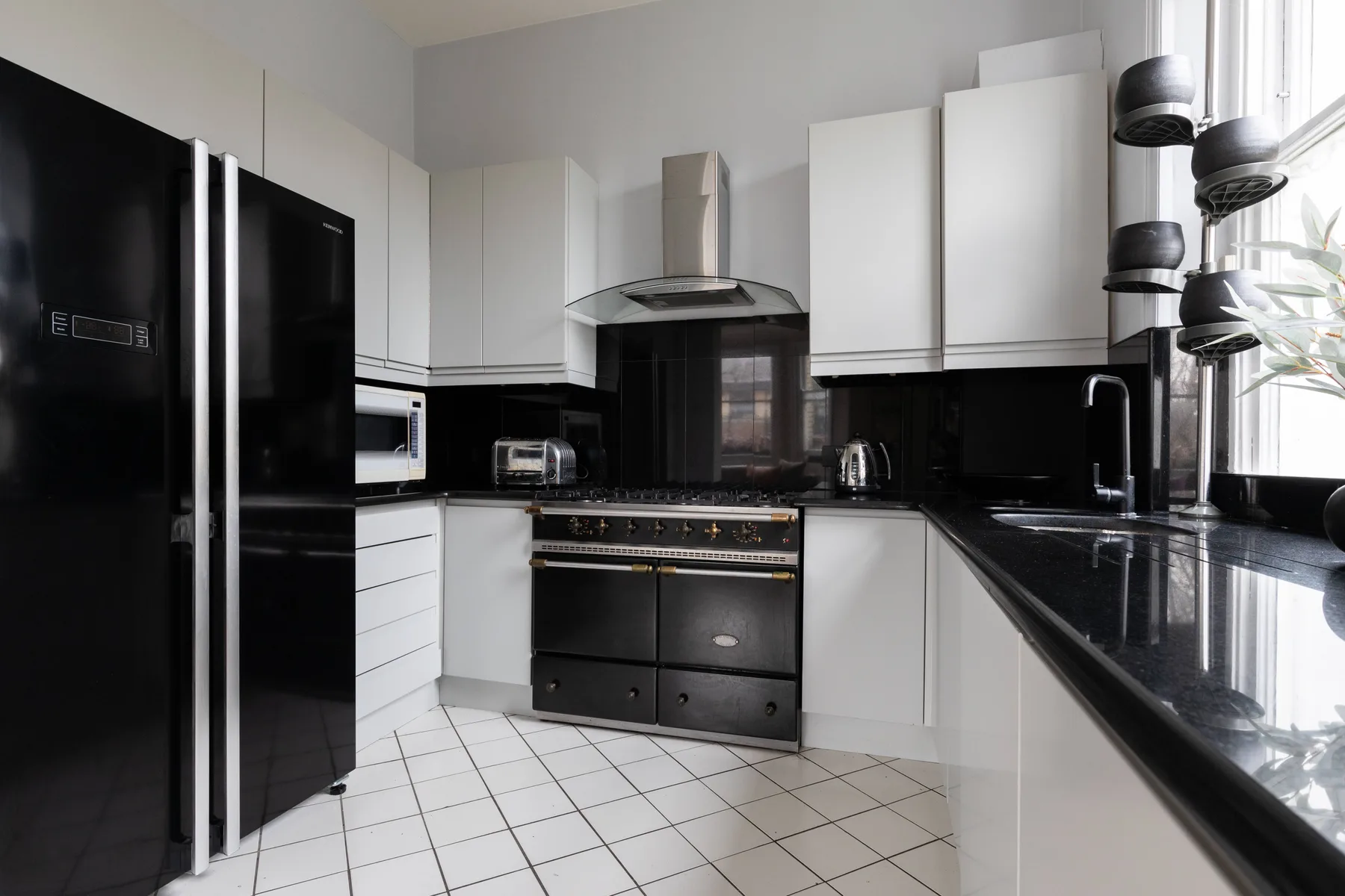 Una cocina moderna con gabinetes blancos, encimeras negras y electrodomésticos de acero inoxidable.