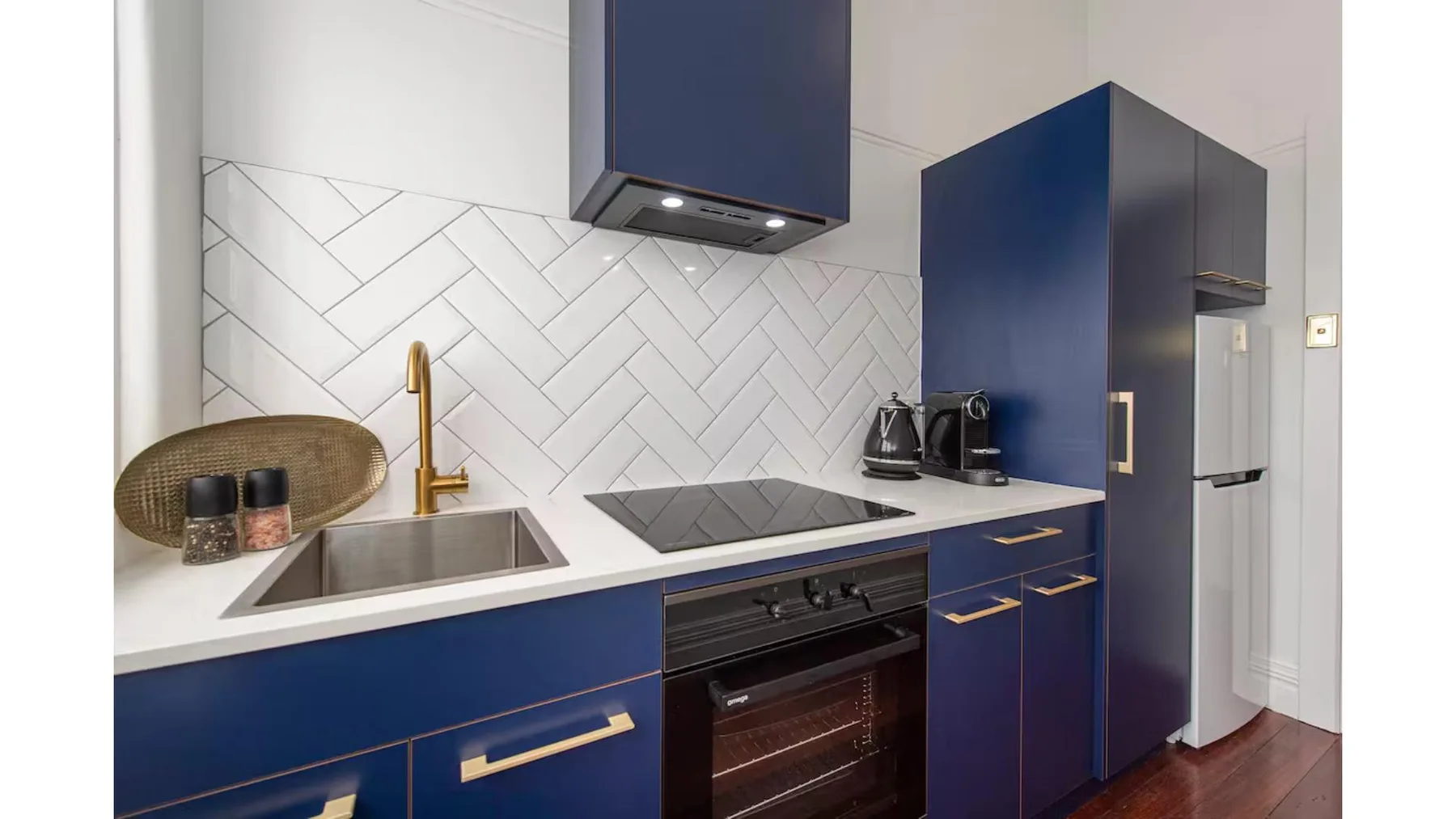 Una cocina moderna con gabinetes azul oscuro, una placa de cocina y un horno.