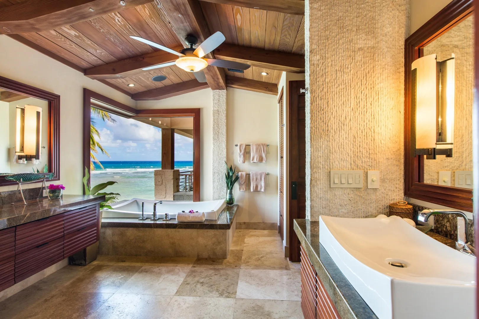 Un baño amplio cuenta con una bañera junto a una gran ventana con vistas al océano.