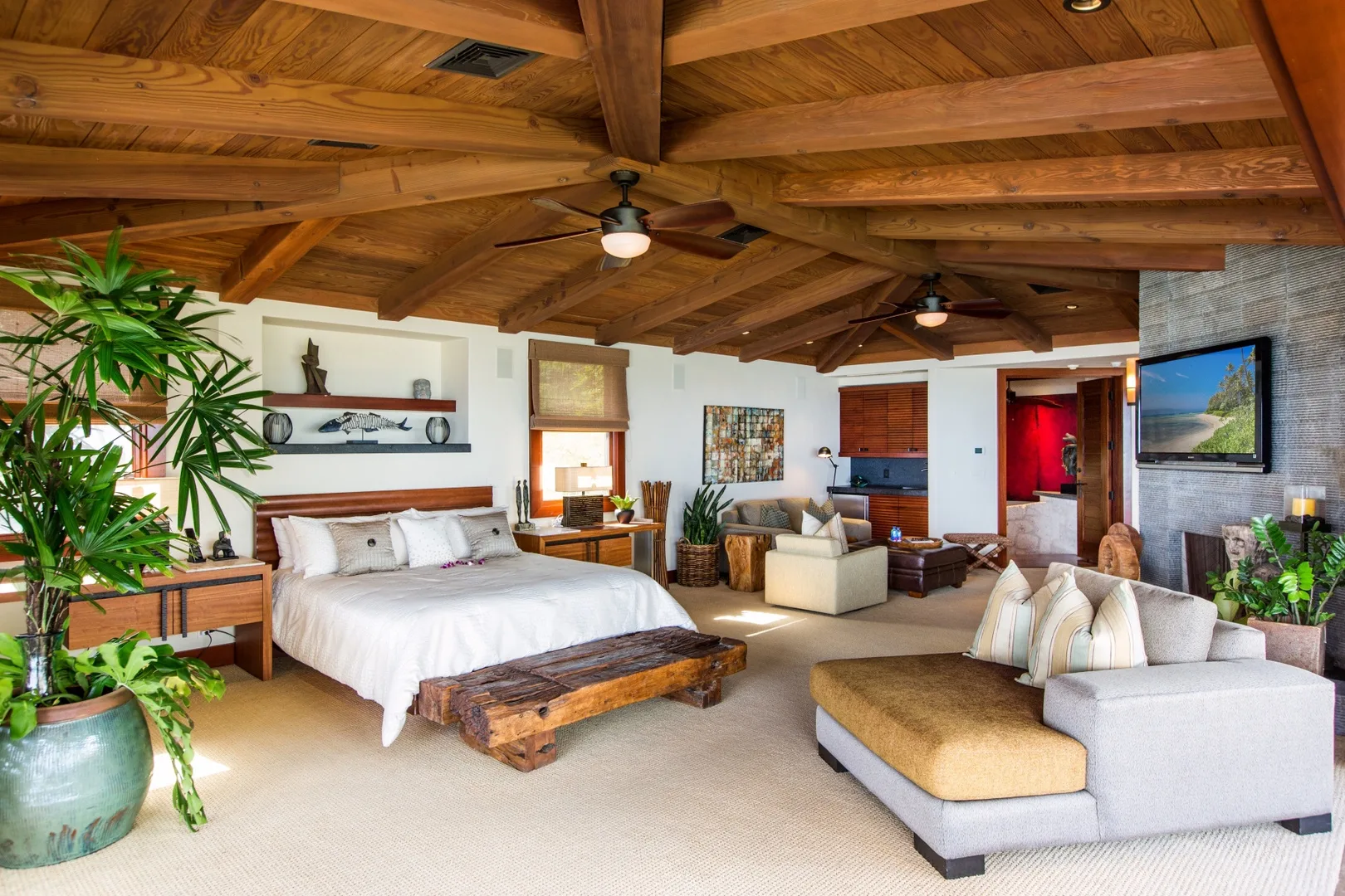 Dormitorio y zona de estar con cama, asientos y vigas de madera a la vista.