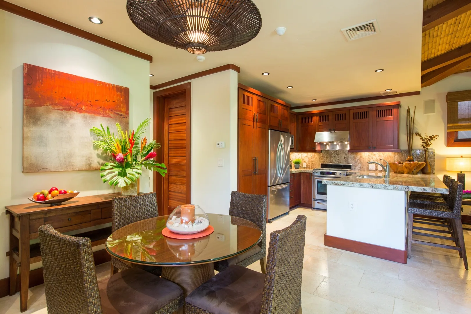 Un comedor se abre a una cocina con gabinetes de madera oscura y una isla central.