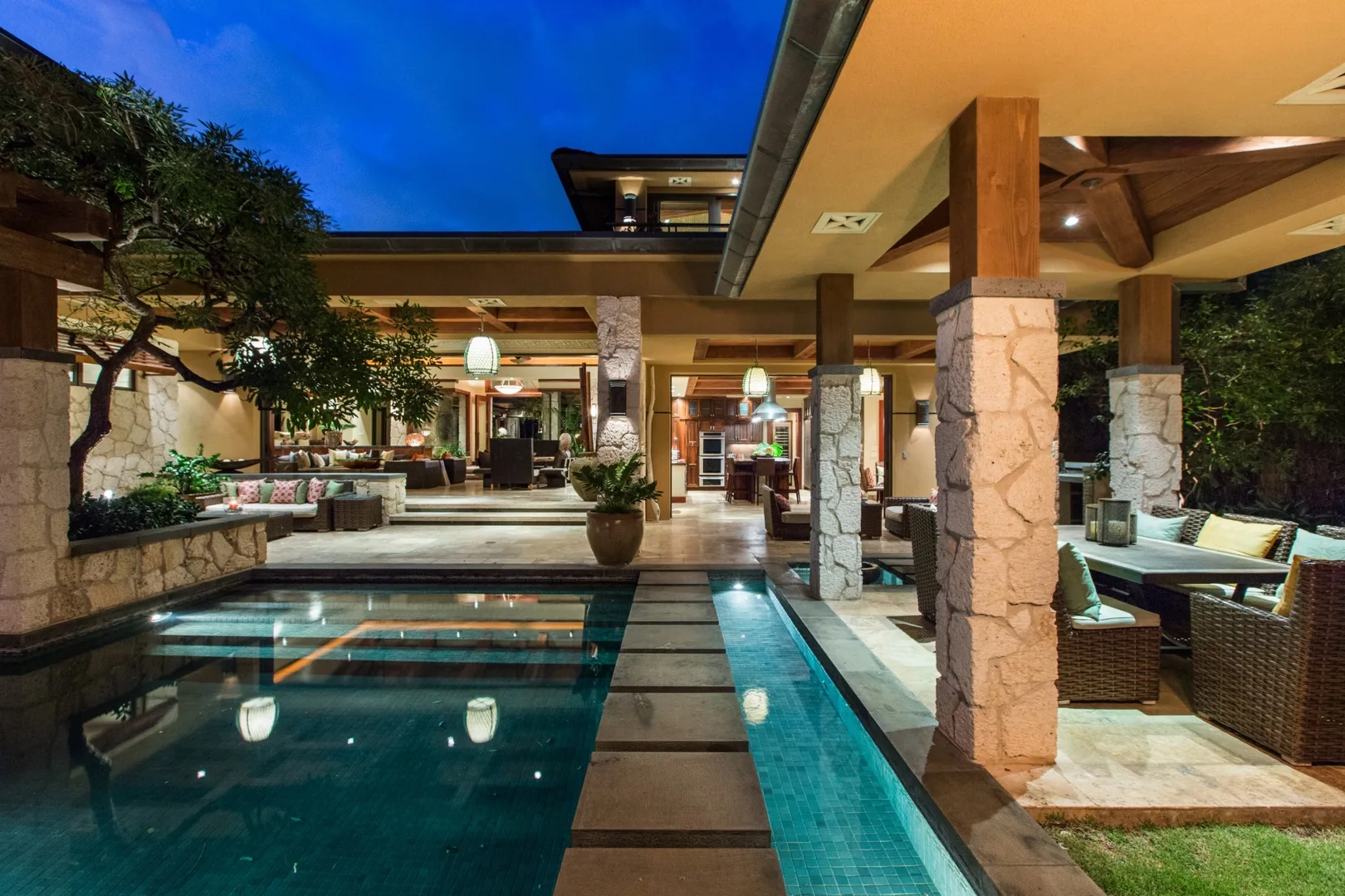 Una piscina exterior cubierta junto a una zona de estar con asientos e iluminación cálida.