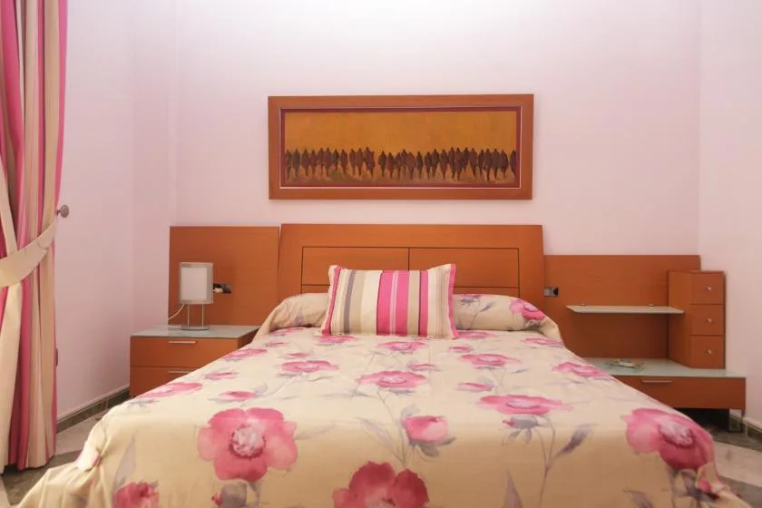 Un dormitorio con una cama cubierta de ropa de cama floral rosa.