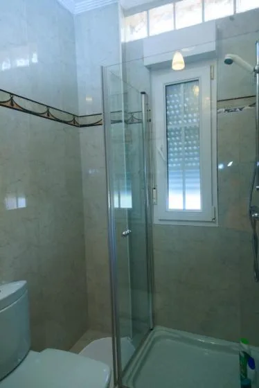 Un baño con una ducha de vidrio y una ventana.