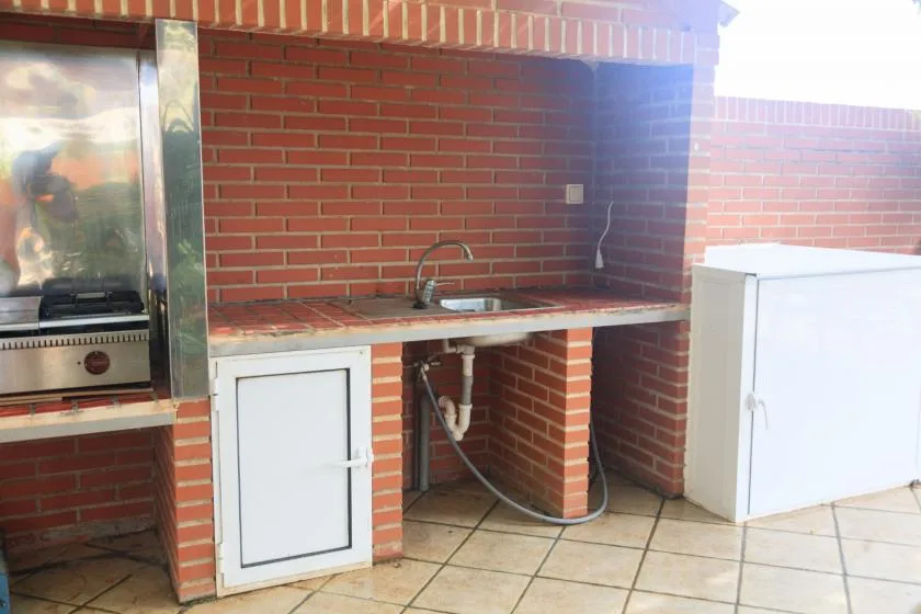 Una encimera de cocina exterior de ladrillo con fregadero y parrilla empotrada.