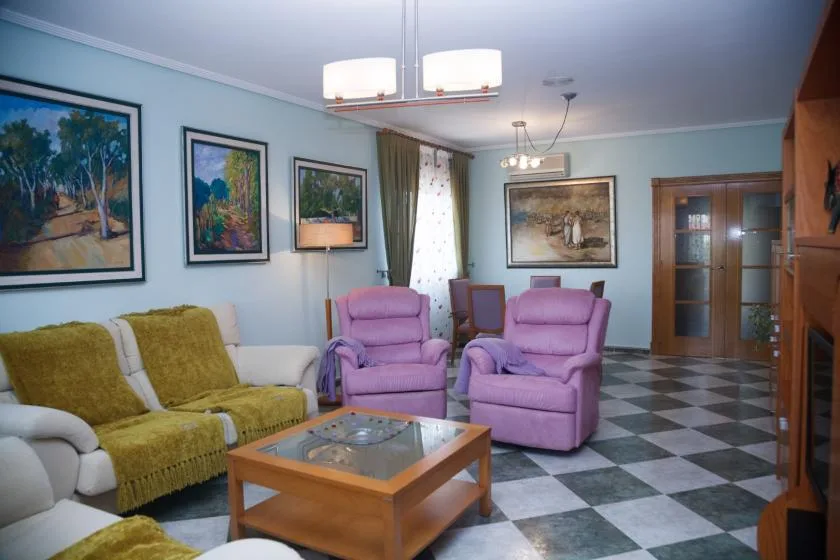 Una sala de estar con asientos alrededor de una mesa de centro con tapa de vidrio.