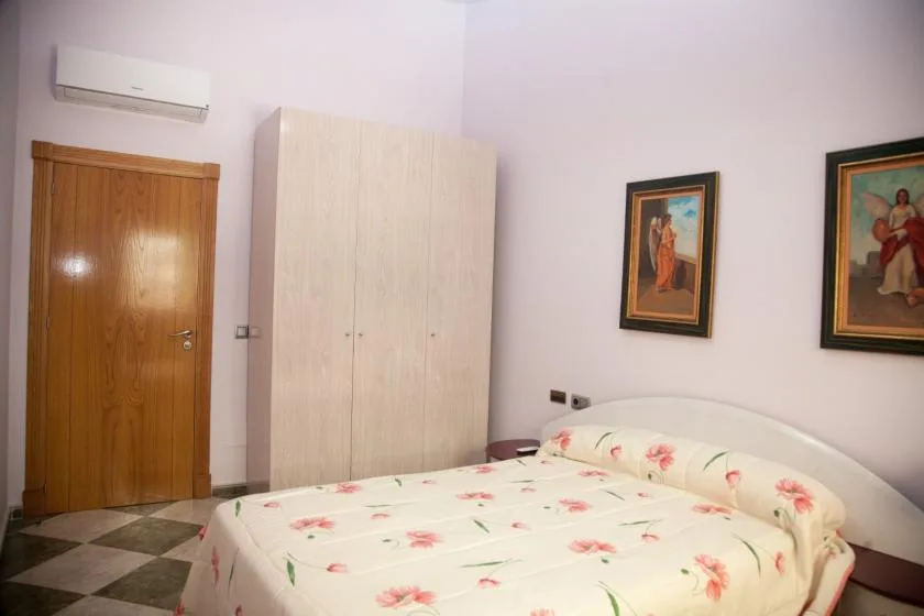 Un dormitorio con ropa de cama floral, un armario y cuadros enmarcados.