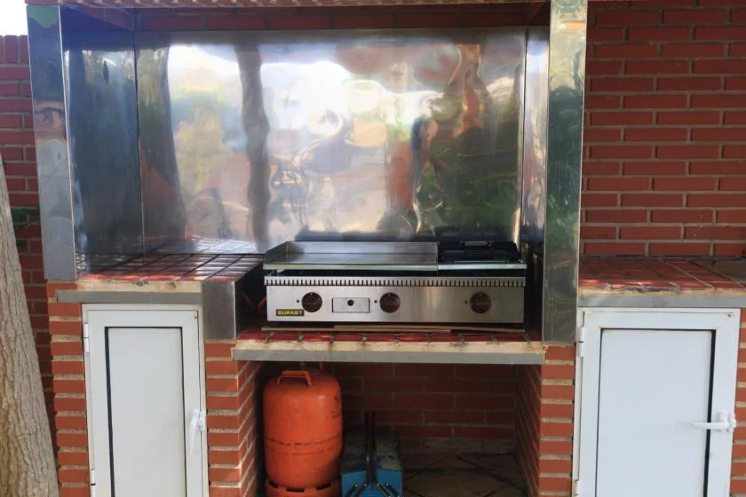 Una zona de cocina exterior con una plancha integrada en una encimera de ladrillo.
