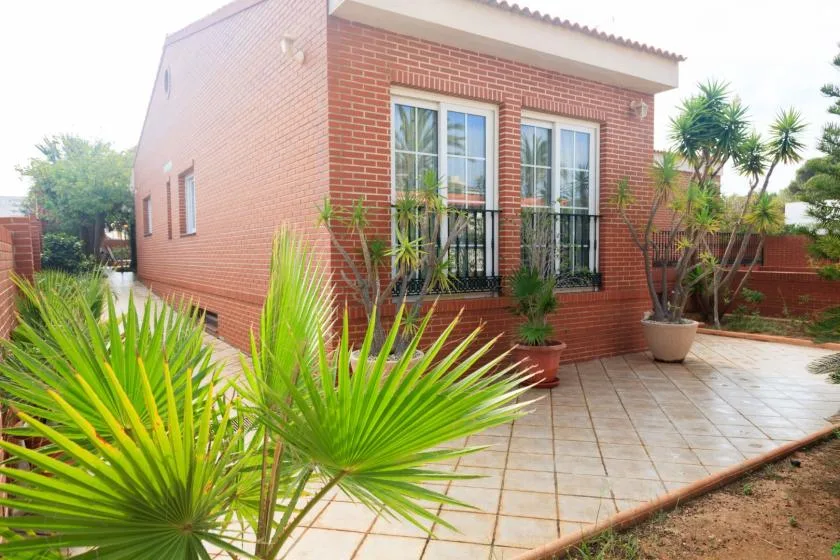 Un edificio de ladrillo da a un patio pavimentado con plantas en macetas.