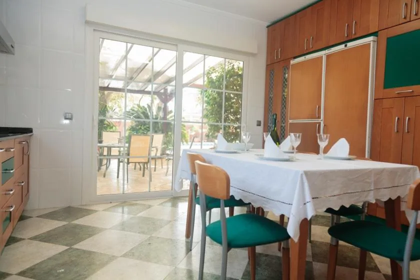 Un comedor con una mesa puesta junto a grandes puertas de vidrio que dan a un patio cubierto.