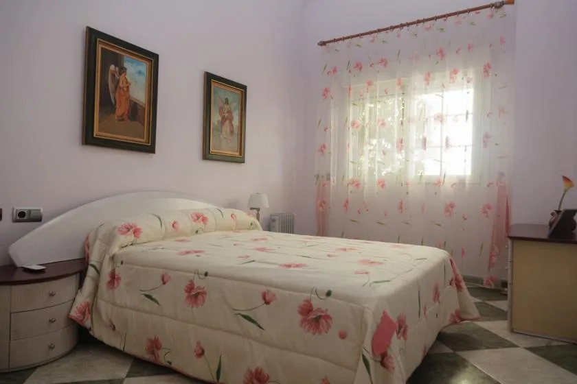 Un dormitorio con una cama cubierta con ropa de cama floral junto a una ventana con cortinas.