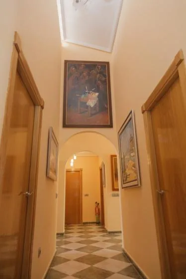 Un pasillo con un arco y cuadros en las paredes.