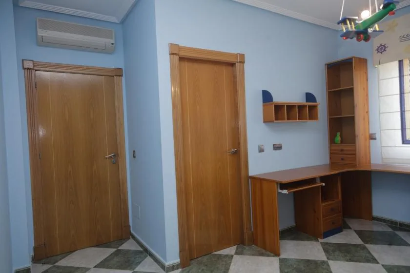 Una habitación azul con puertas de madera, escritorio y estantes.