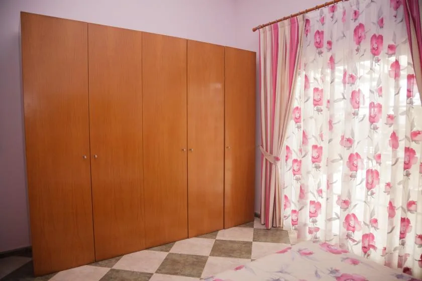 Dormitorio con un gran armario de madera y cortinas florales rosas.