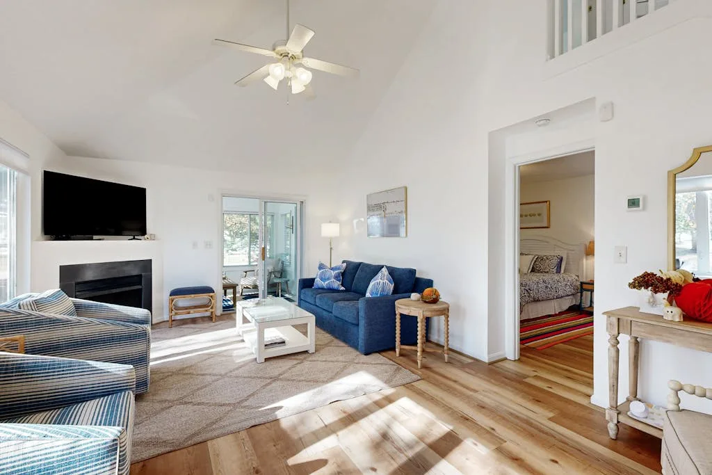 A bright living room with blue seating, a coffee table, and a ceiling fan.