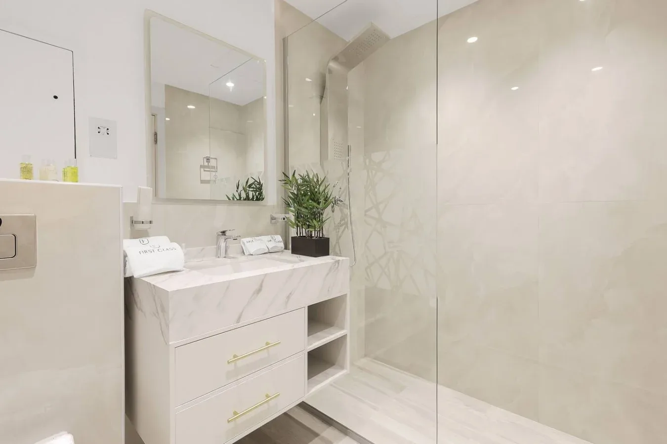 A bright bathroom with a vanity, mirror, and glass shower.