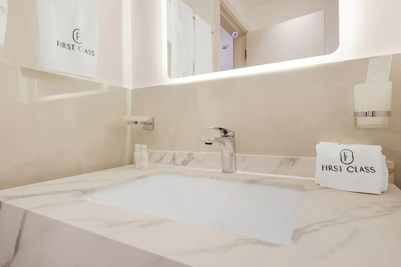 A bathroom vanity with a white sink, chrome faucet, and large mirror.