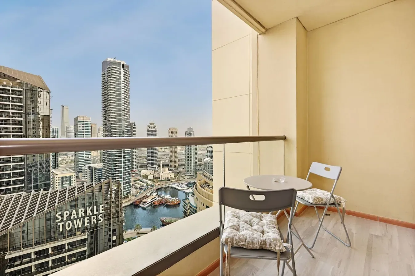 A balcony seating area overlooks a city skyline and waterfront.