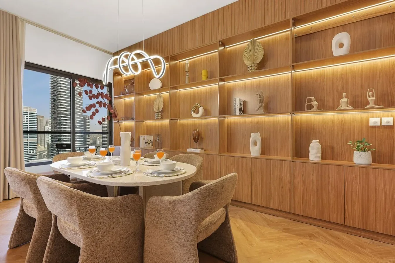 A dining area with a set table beside illuminated wooden shelves.
