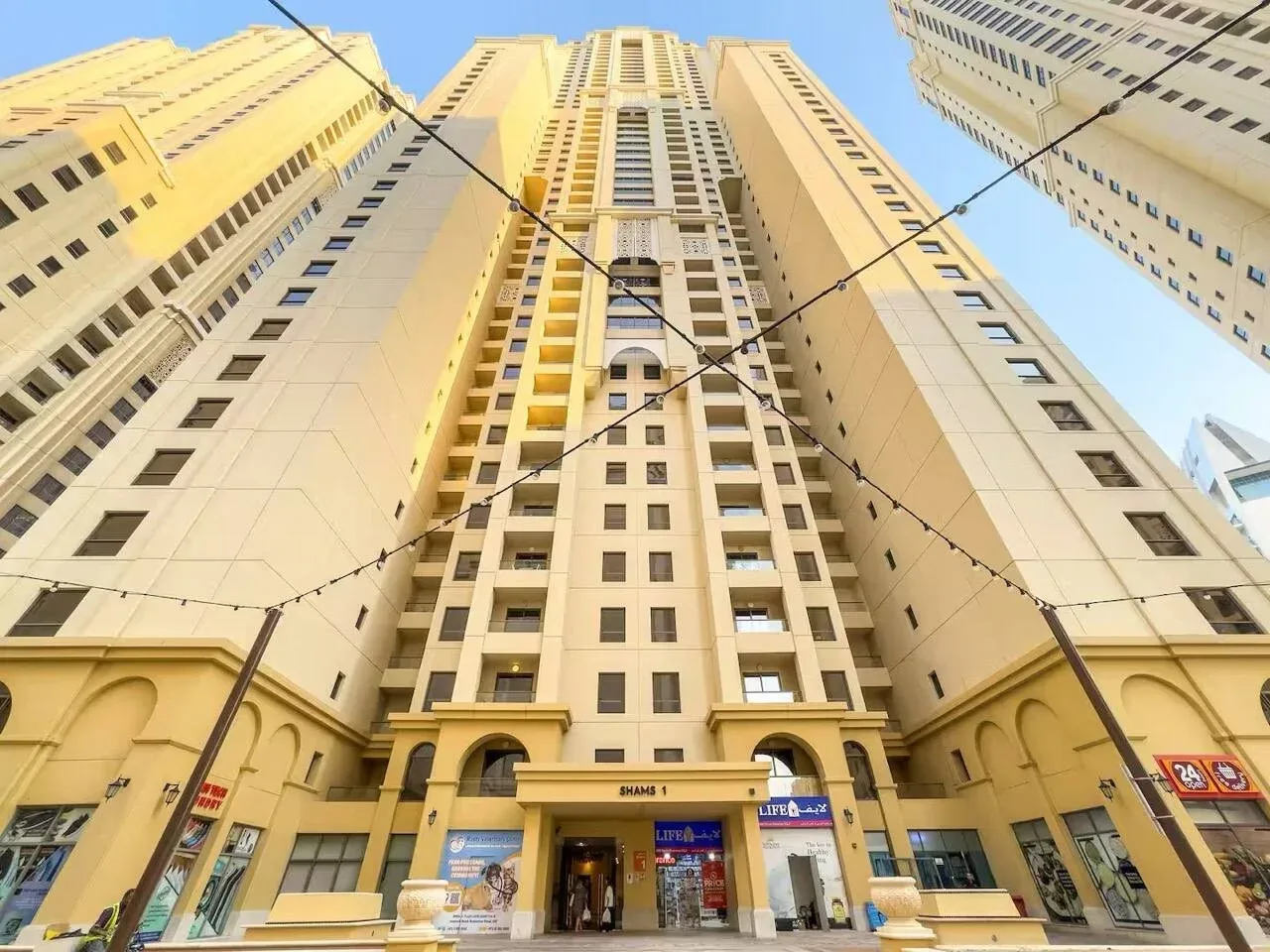 Tall beige high-rise buildings rise above street-level storefronts.