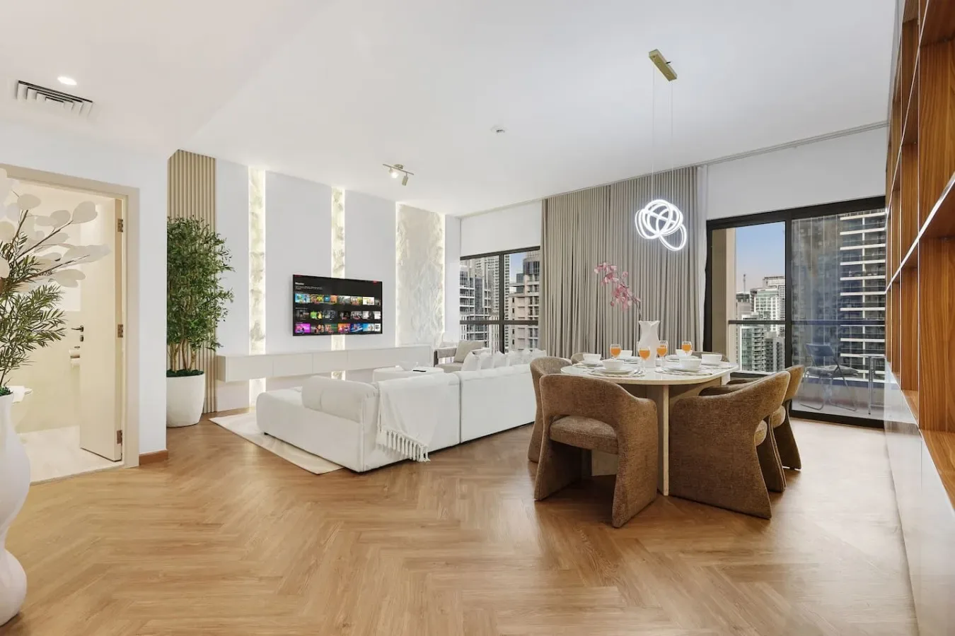 A bright open-plan living and dining area with large windows and contemporary seating.