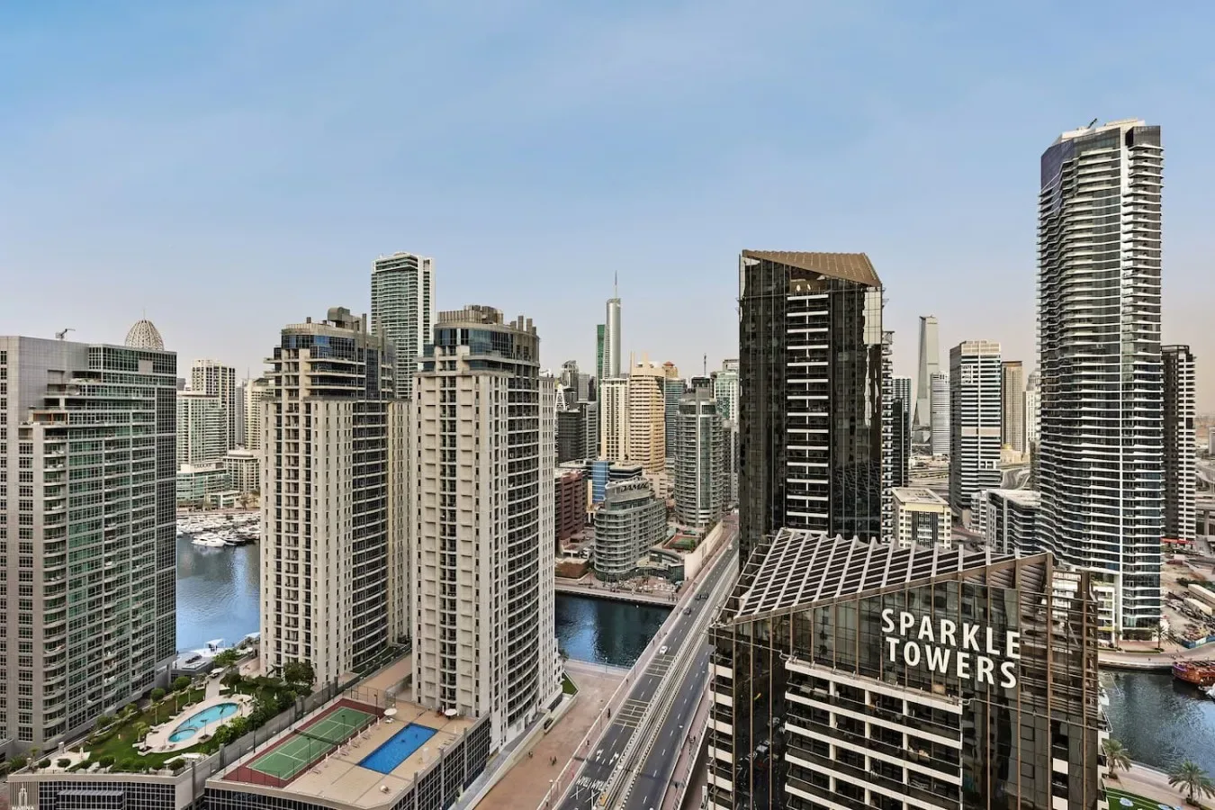 City skyline with tall buildings, a canal, and a road in the foreground.