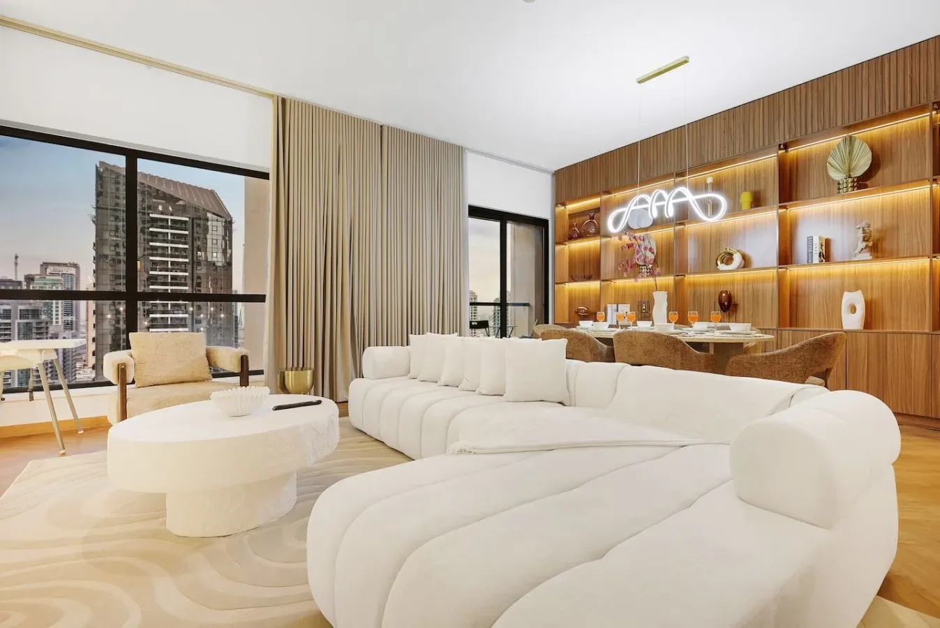 A bright living room with curved white seating and a wood-paneled display wall.
