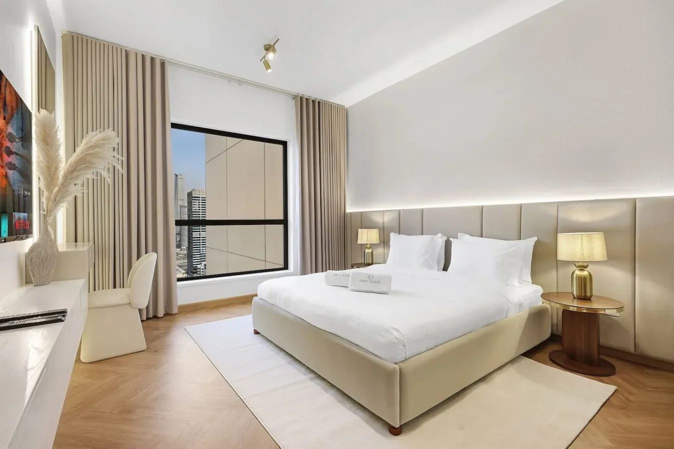 A bright bedroom with a large bed, bedside lamps, and a window with curtains.