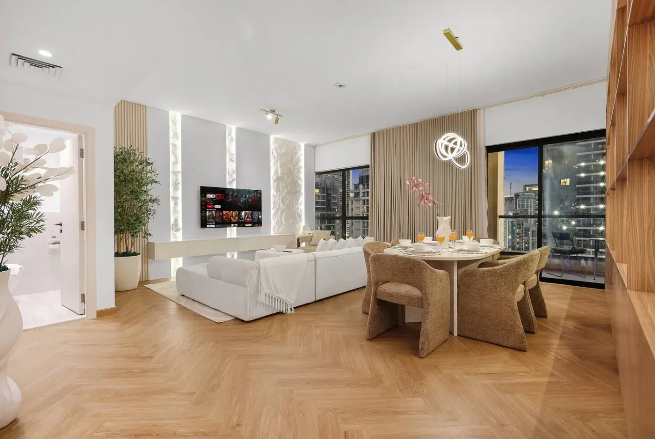 A modern open-plan living and dining room with seating, a table, and large windows.