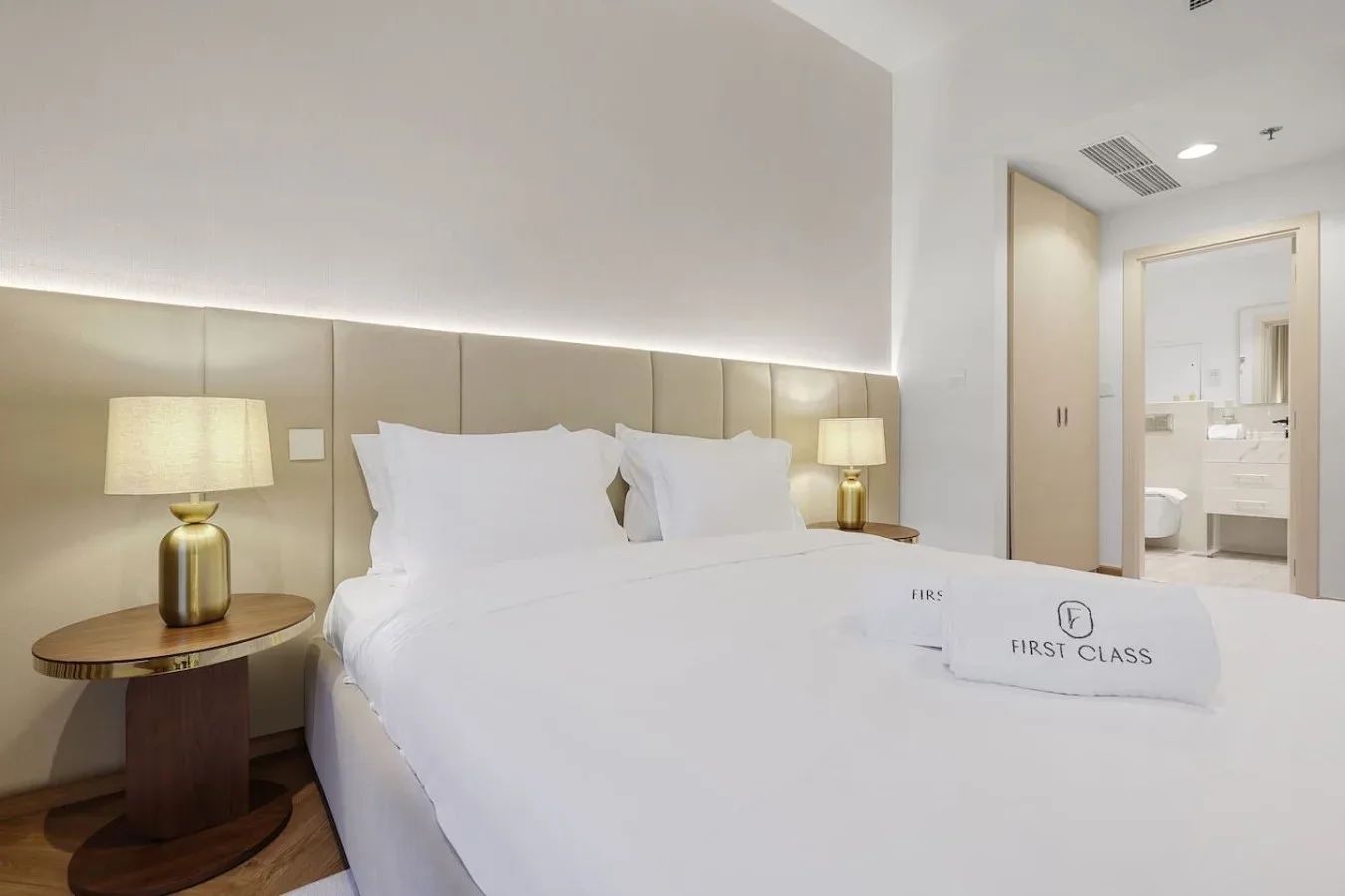 A hotel bedroom with a neatly made bed and bedside lamps.