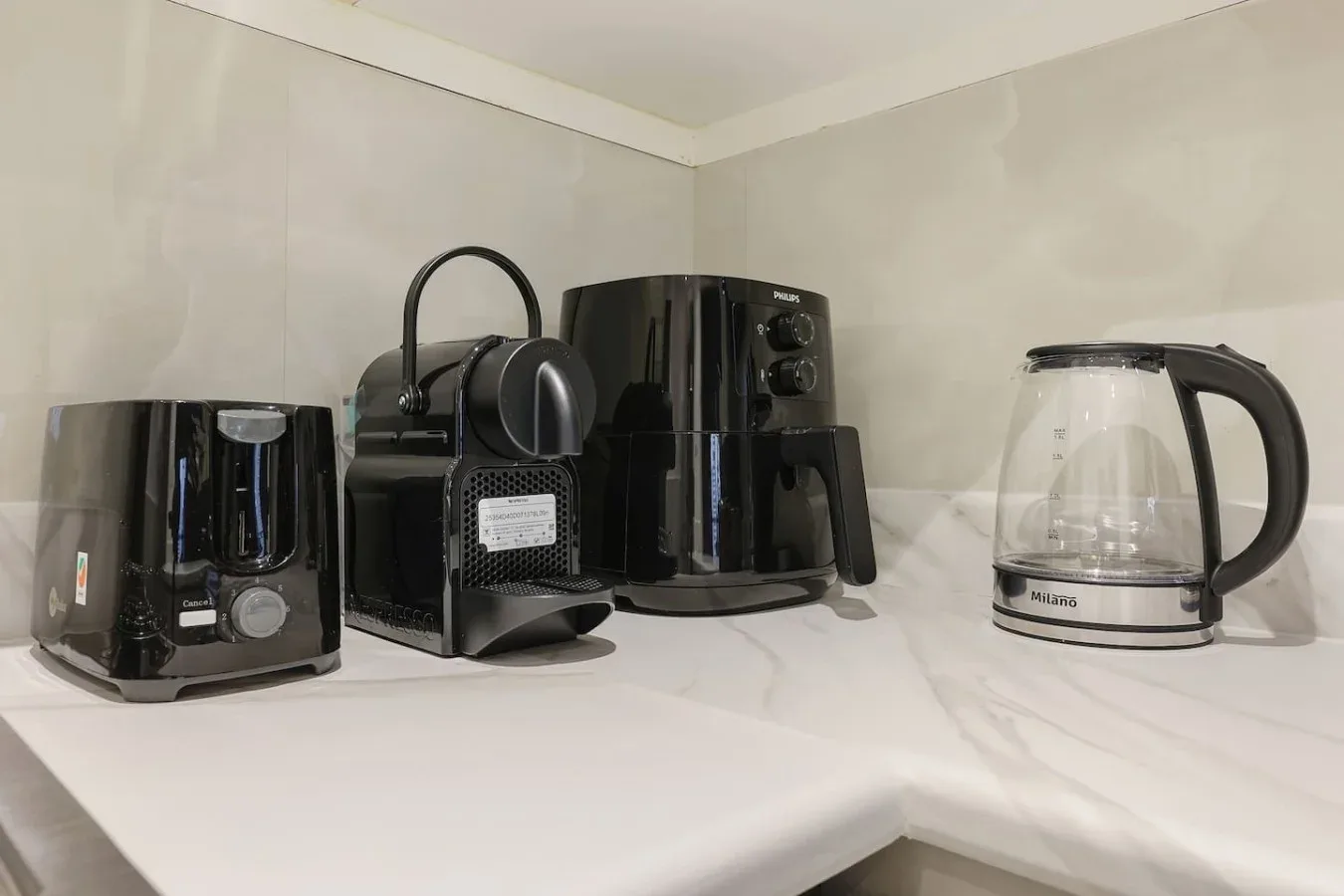 A kitchen counter holds several small appliances, including a coffee maker and glass kettle.