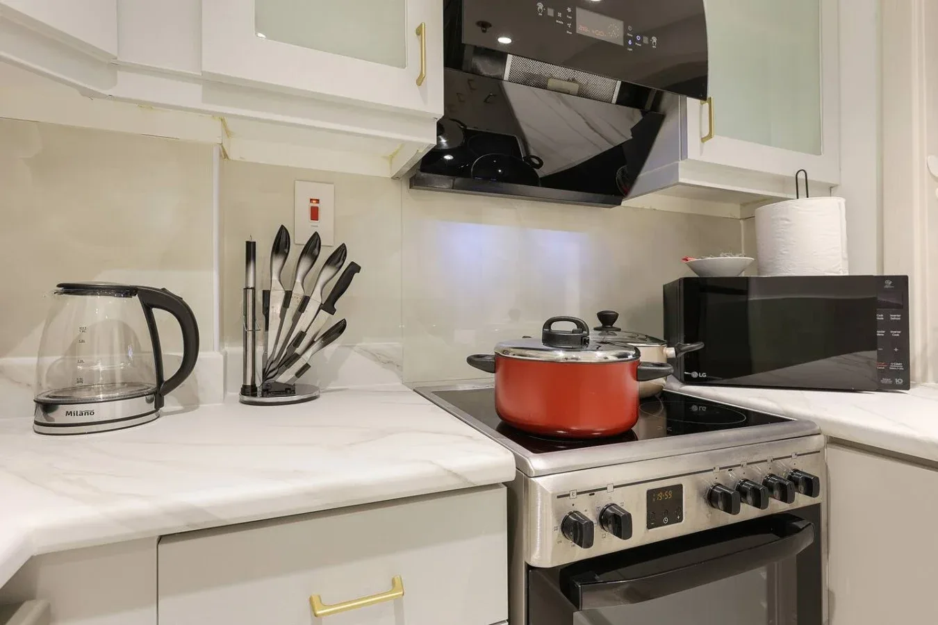A kitchen counter with a red pot on the stove and small appliances nearby.