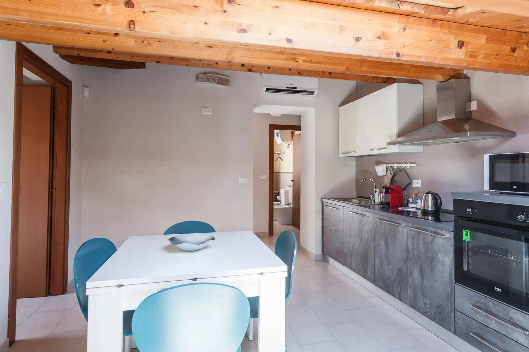 Una cocina y comedor con una mesa blanca y gabinetes grises.