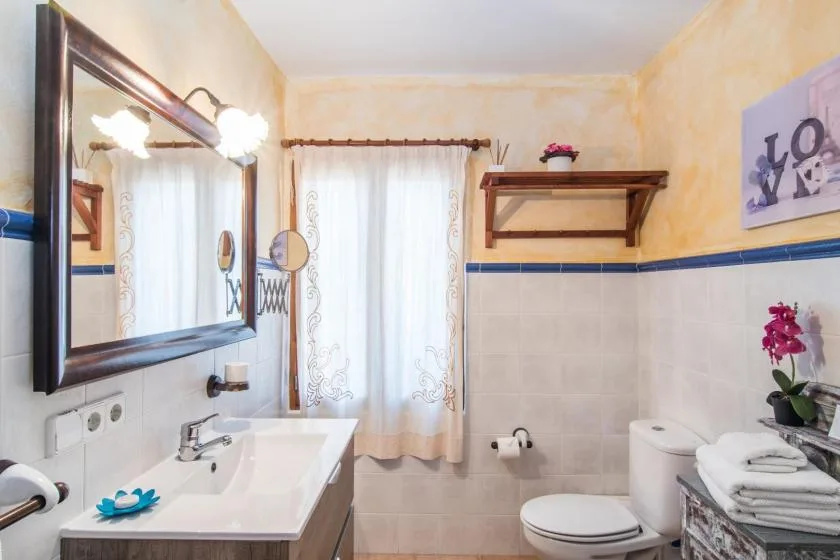 Un baño con lavabo, inodoro y una ventana con cortina.