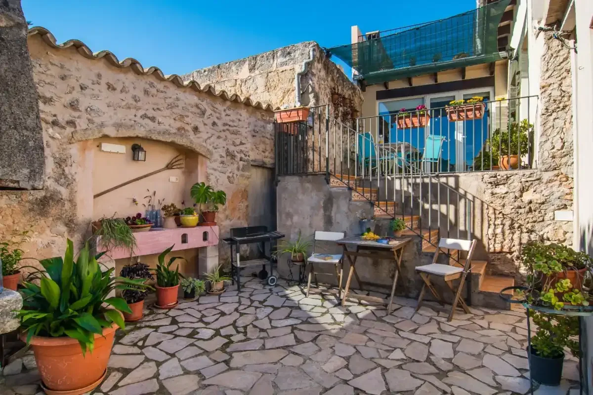 Un patio de piedra con asientos al aire libre y plantas en macetas.