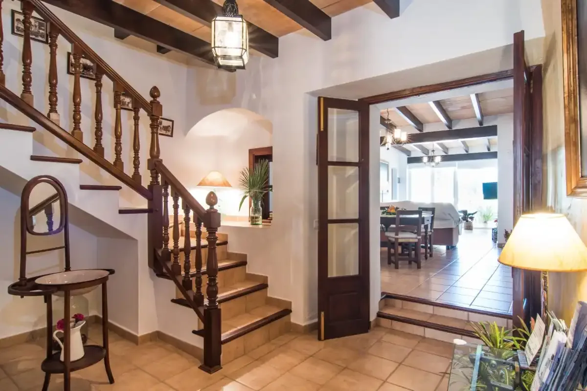 Una escalera y una puerta abierta dan a una zona de comedor y estar.