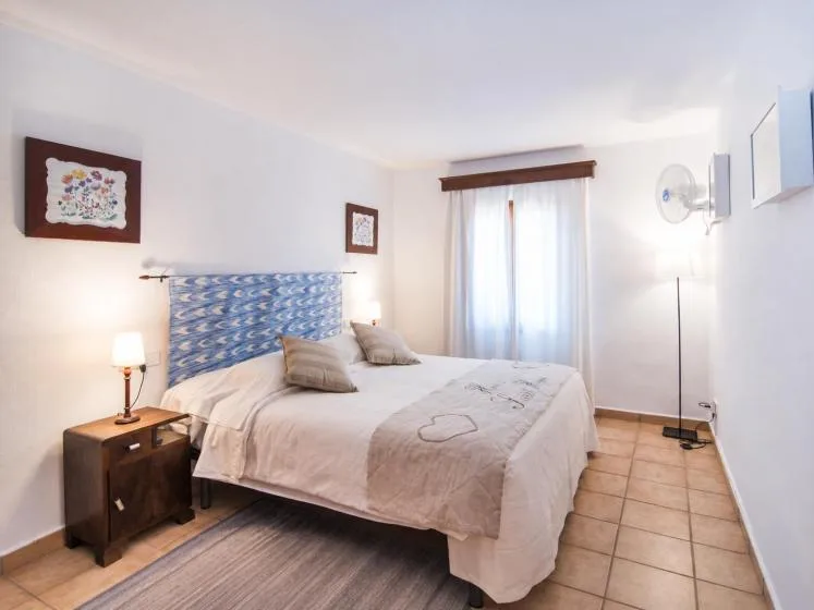 Un dormitorio con una cama junto a una ventana con cortinas y suelo de baldosas.