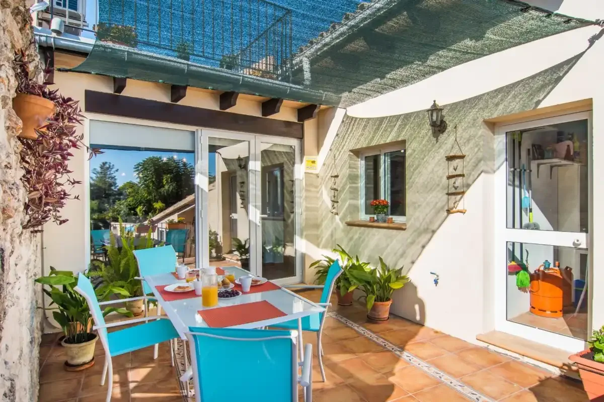 Un patio soleado con mesa de comedor y asientos coloridos.