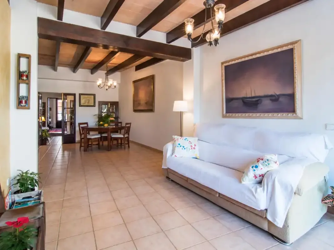 Una sala de estar con asientos blancos y una mesa de comedor bajo vigas expuestas.