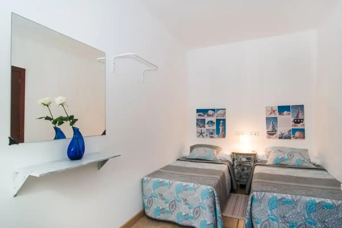 Un dormitorio con dos camas individuales y cuadros de temática costera en la pared.