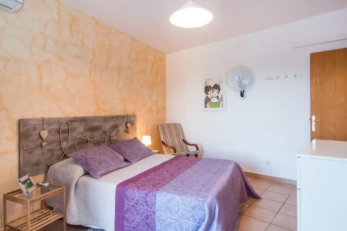 Un dormitorio con una cama doble y un sillón a rayas.