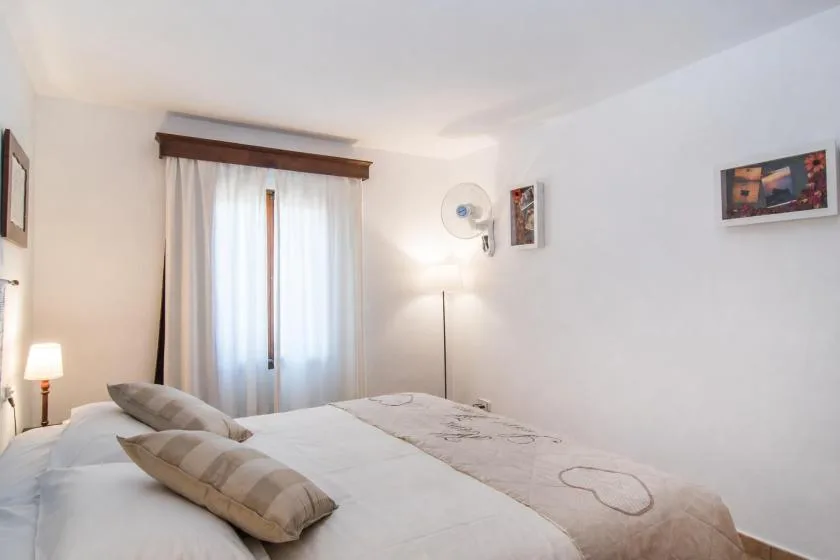 Un dormitorio luminoso con una cama tendida y cortinas transparentes.