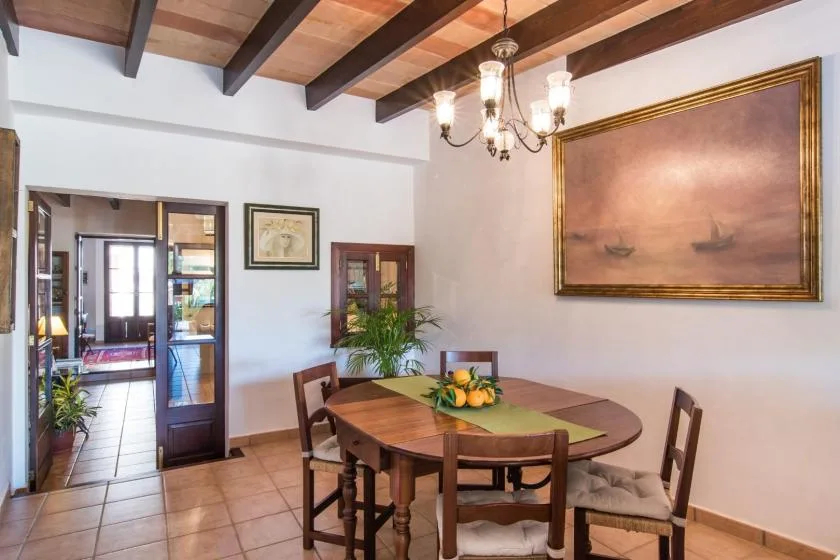Un comedor con una mesa de madera bajo vigas de techo expuestas.