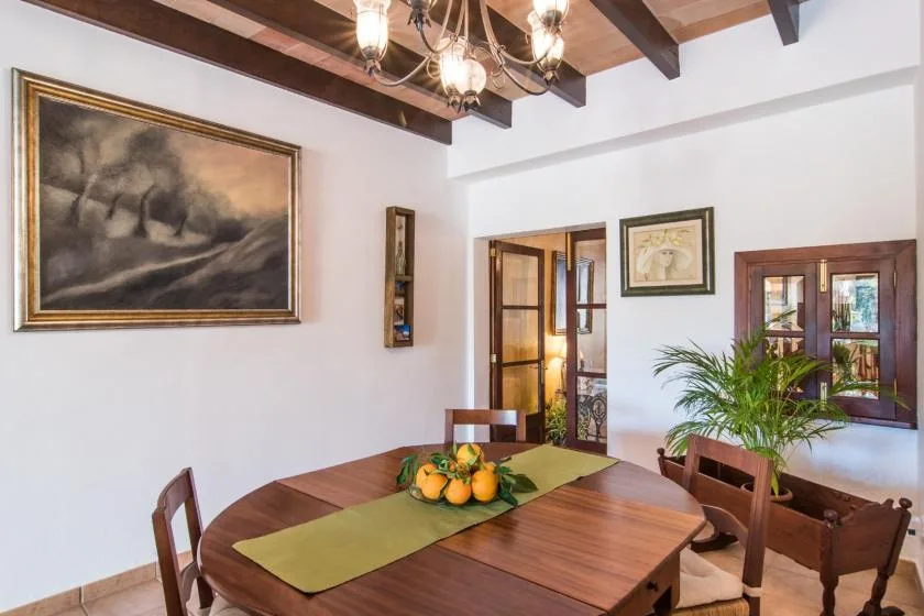 Un comedor con una mesa de madera, un camino verde y cuadros enmarcados.