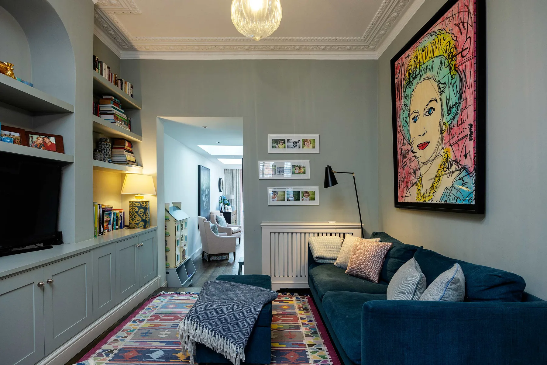 A living room with a blue sofa, built-in shelving, and colorful wall art.