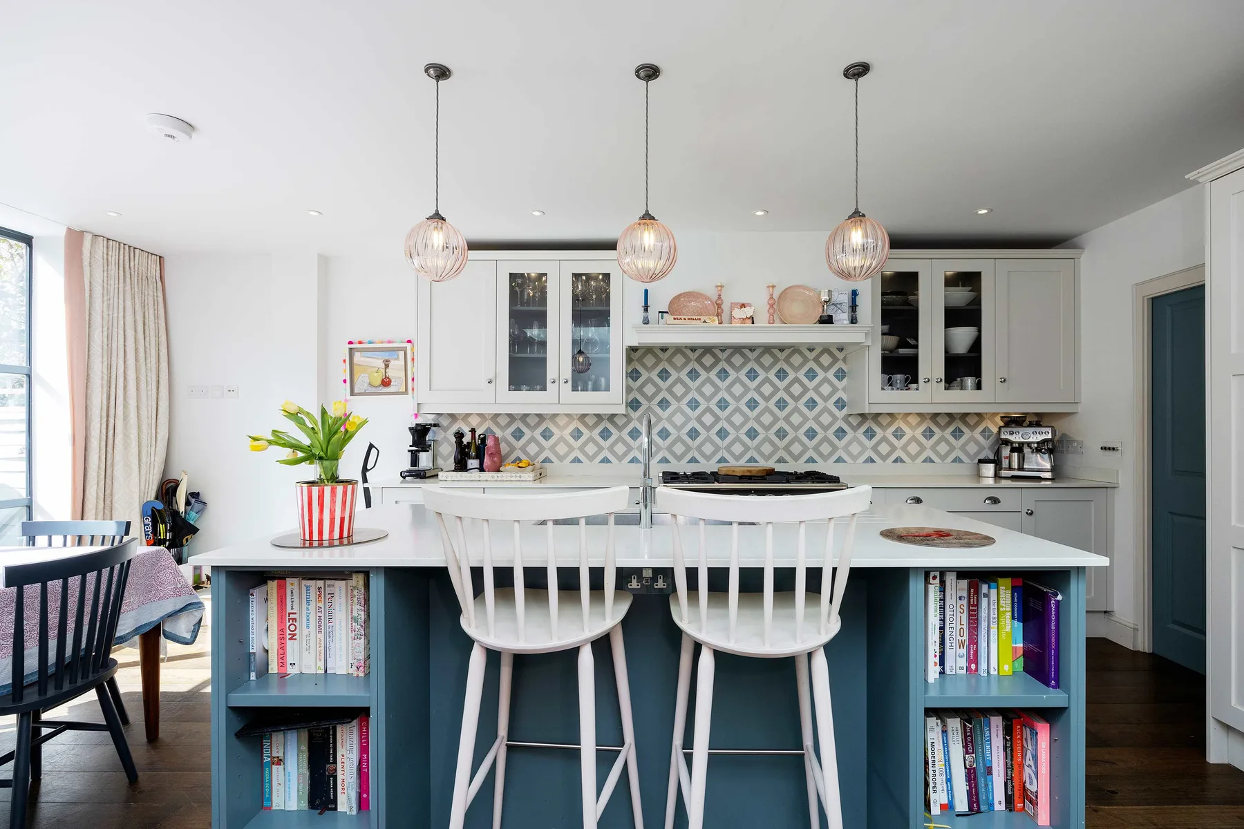 A bright kitchen with a central island, bar seating, and patterned tile backsplash.