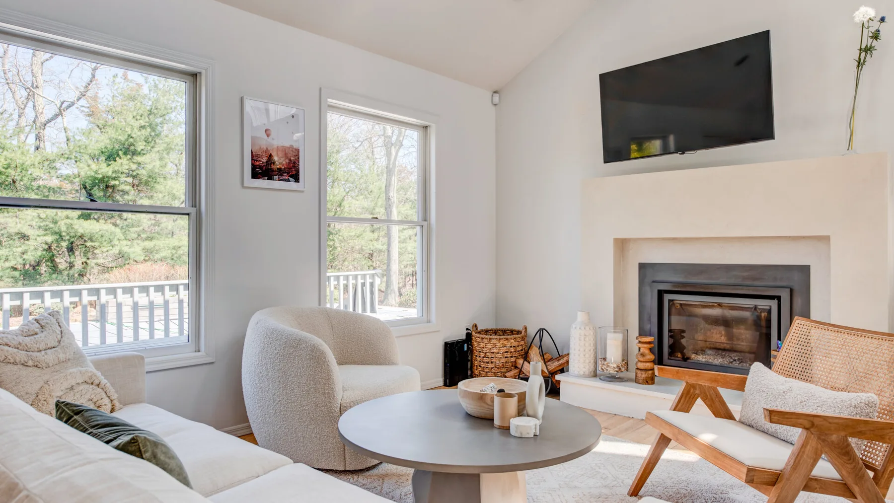 Una luminosa sala de estar con chimenea, asientos y grandes ventanas con vistas a la vegetación.