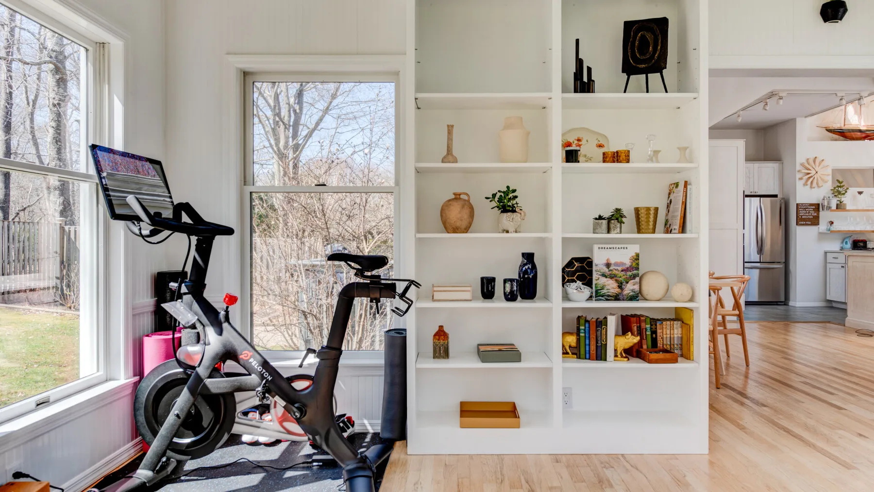 Una luminosa sala de concepto abierto tiene bicicletas estáticas junto a una estantería empotrada.