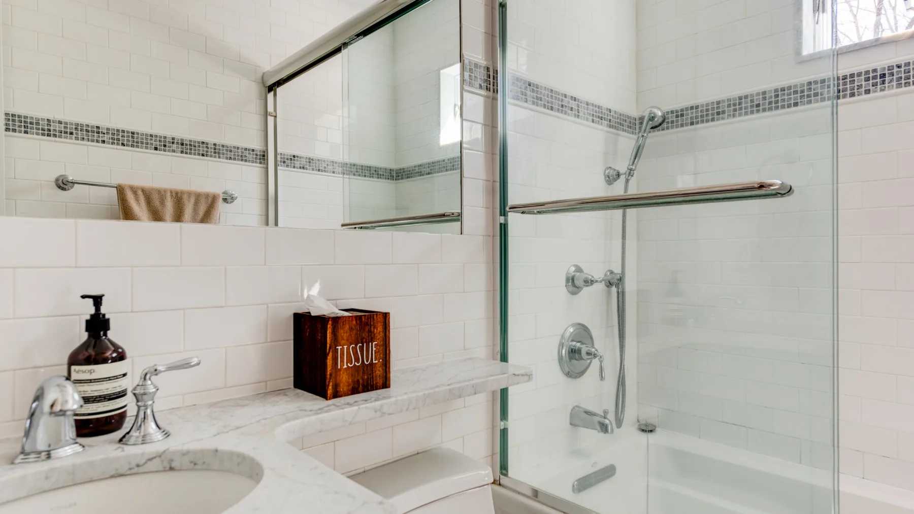 Un baño alicatado con una ducha de vidrio y un lavabo de mármol.